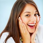 Closeup of surprised girl holding her face and smiling