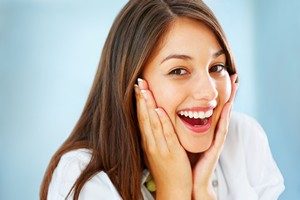 Closeup of surprised girl holding her face and smiling