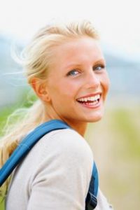 Portrait of a pretty young college student laughing outdoors